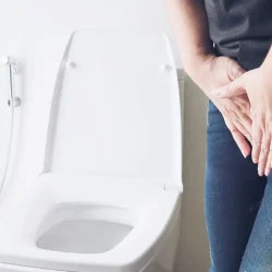 Woman holding hand near toilet bowl - health problem concept